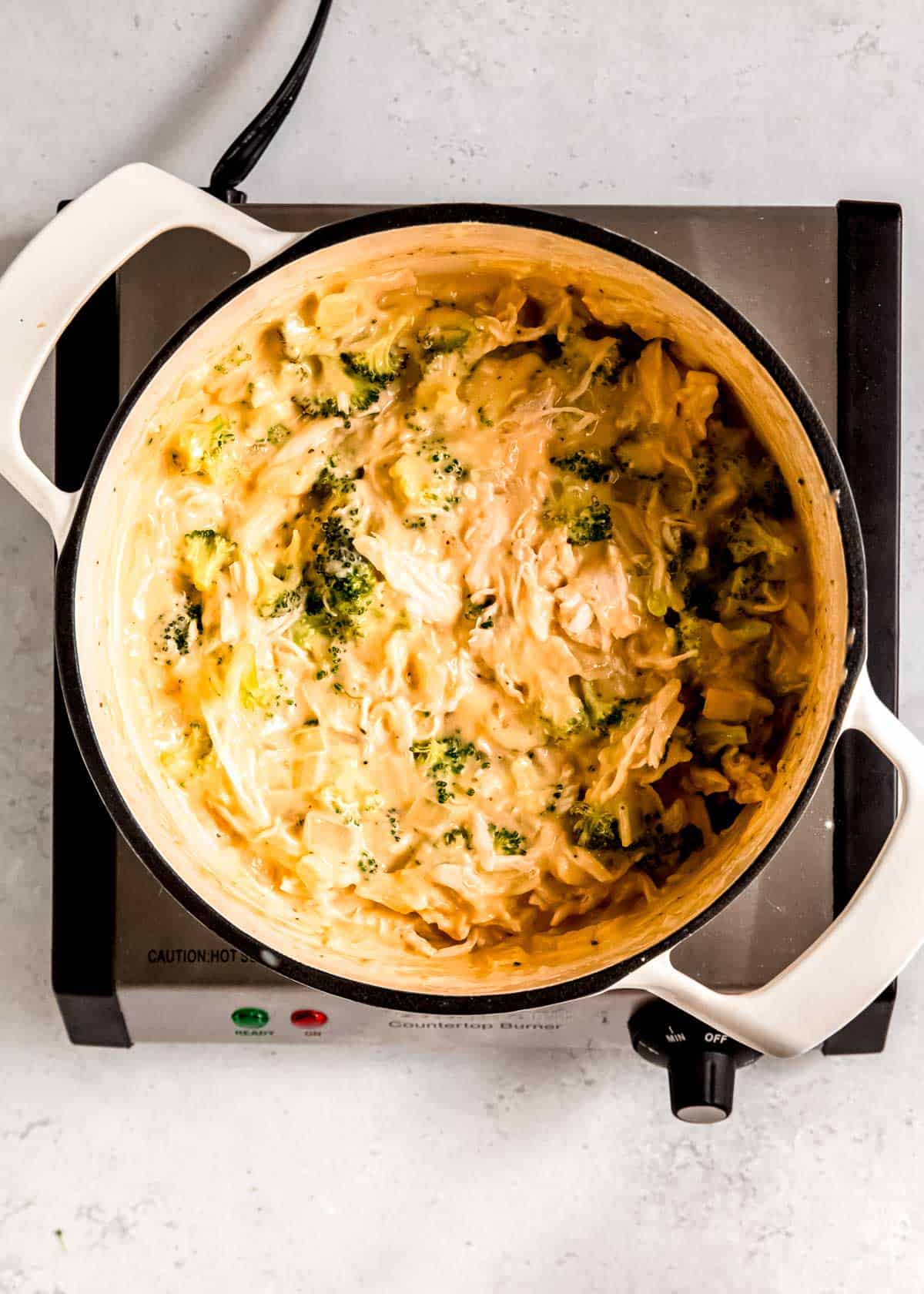 creamy pot pie filling in a pan with chicken, broccoli, cheese, and onions