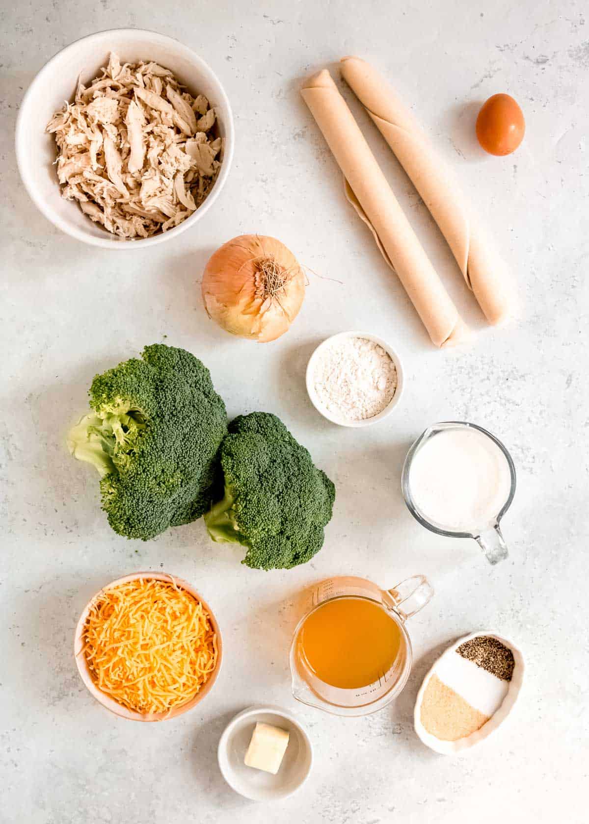 all ingredients needed for a broccoli cheddar chicken pot pie on a marble countertop