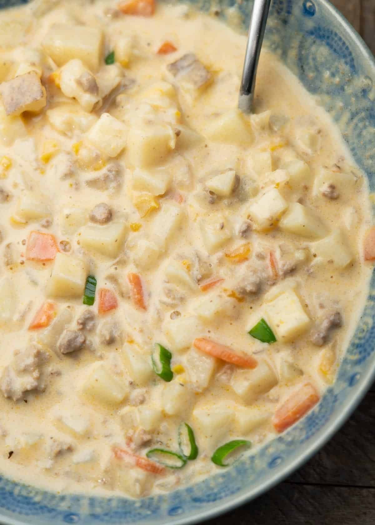 a bowl full of creamy, cheesy hamburger soup with potatoes