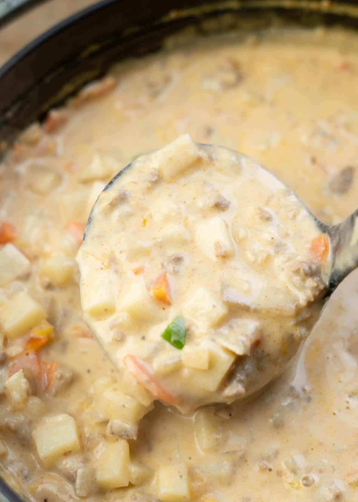 a ladle filled with creamy hamburger potato soup