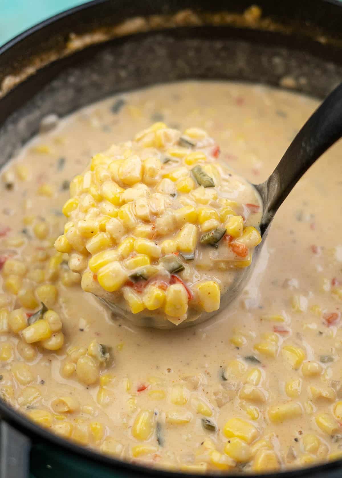 cast iron dutch oven full of Mexican Street Corn Soup; a ladle taking out a big scoop