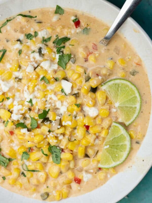 a white bowl filled with Mexican Street Corn Soup, garnished with lime wedges