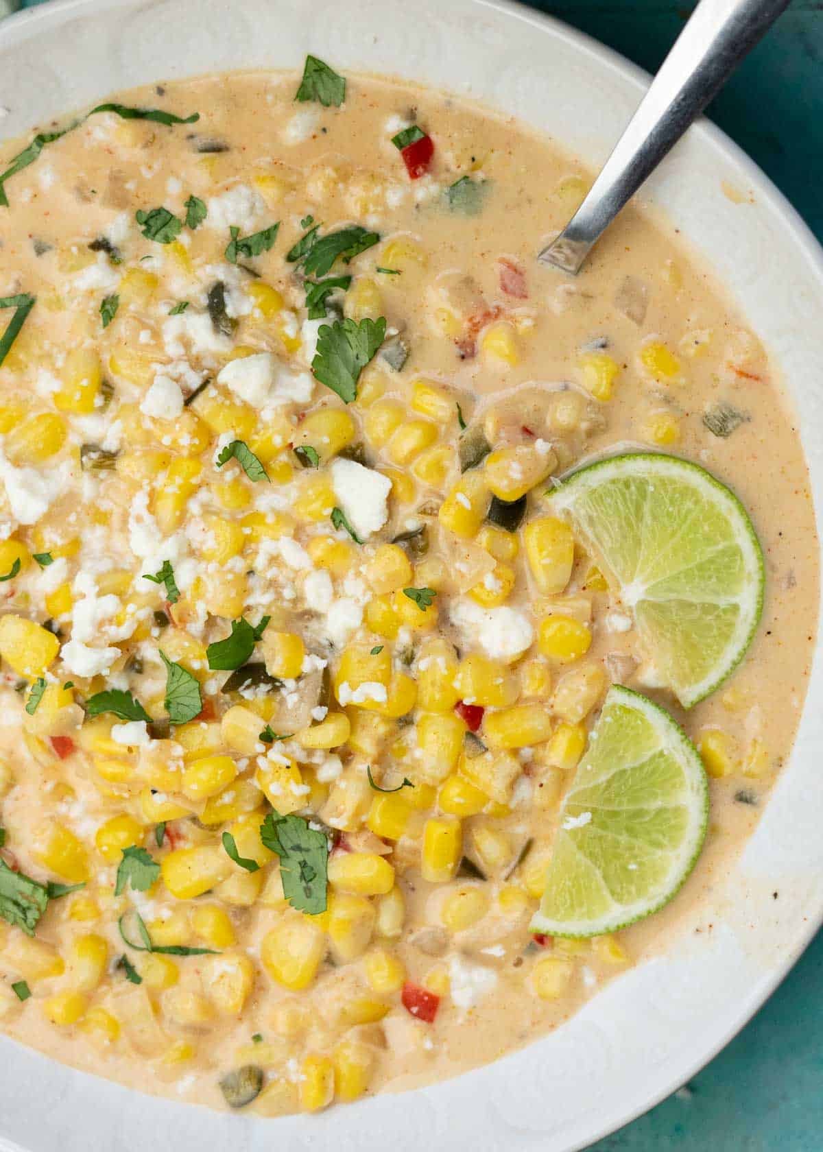 a white bowl filled with Mexican Street Corn Soup, garnished with lime wedges