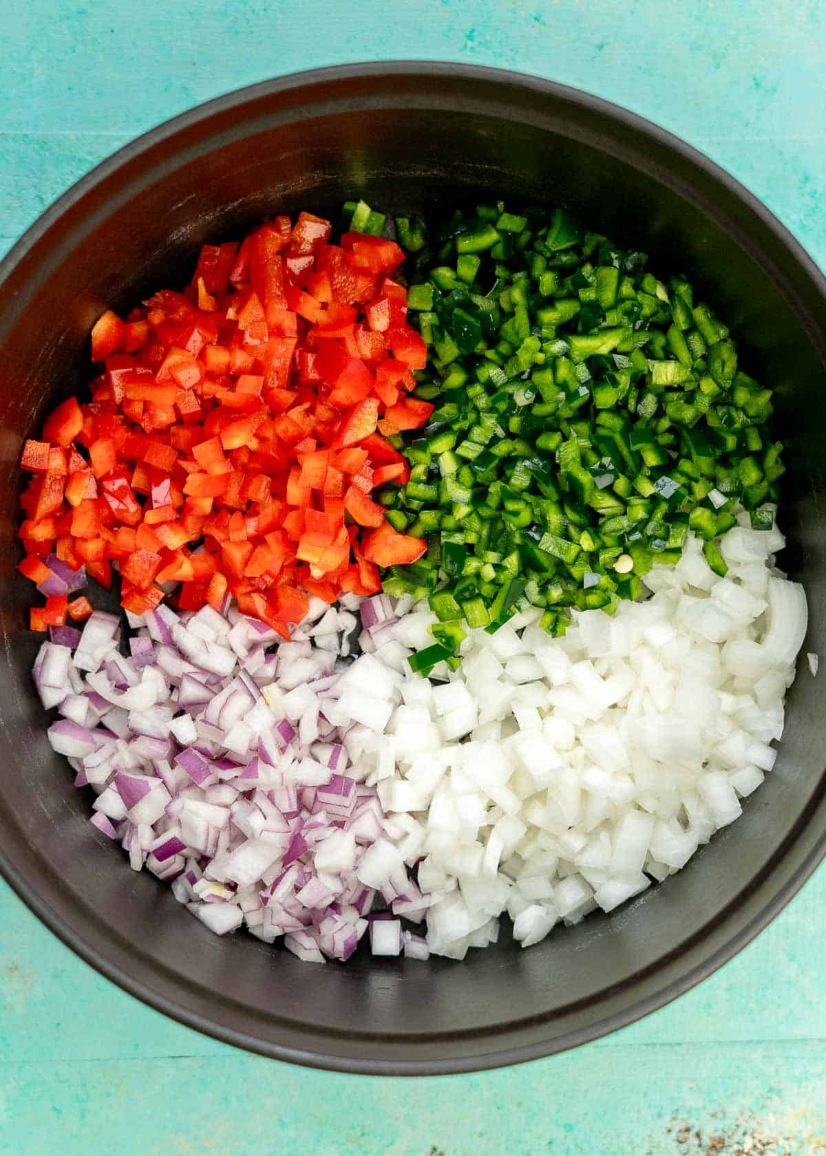 diced red bell pepper, poblano pepper, jalapeno pepper, red onion, and white onion in a cast iron dutch oven