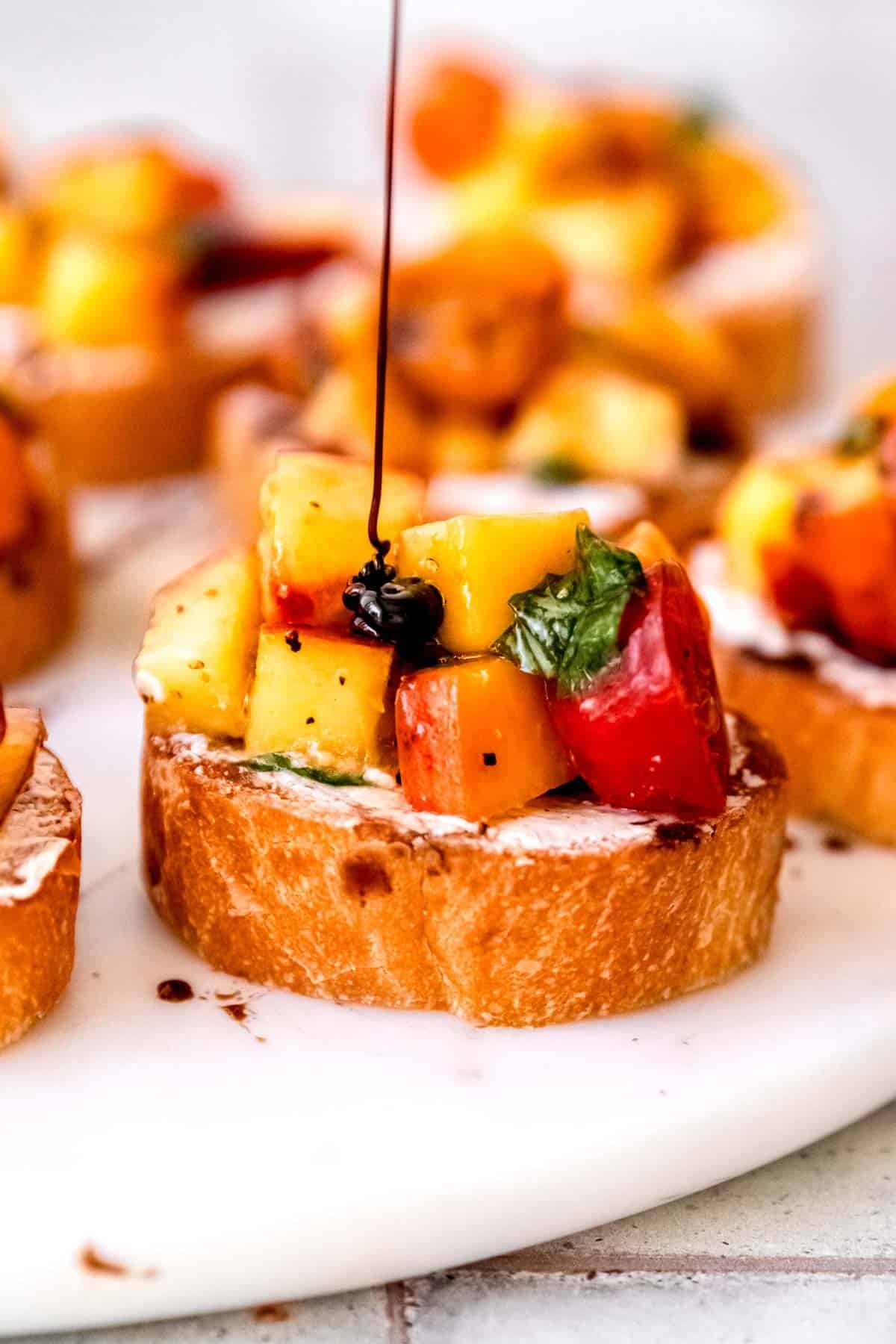 This amazing peach bruschetta is topped with a drizzle of balsamic glaze.