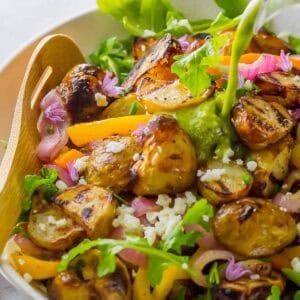 grilled vegetables over arugula and tossed with a lemon vinaigrette dressing in a white bowl