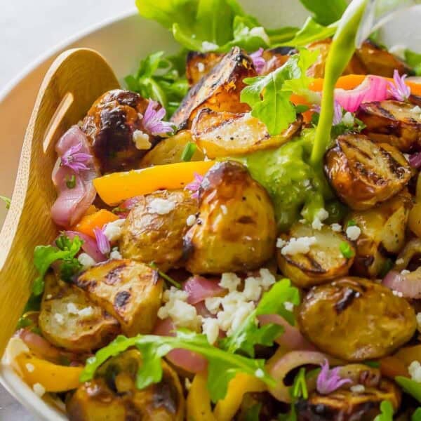 grilled vegetables over arugula and tossed with a lemon vinaigrette dressing in a white bowl