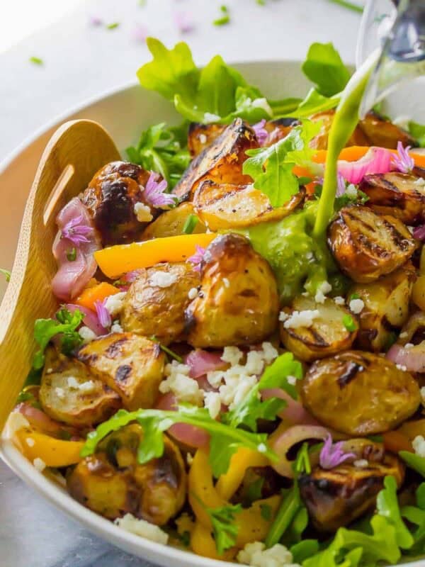 grilled vegetables over arugula and tossed with a lemon vinaigrette dressing in a white bowl