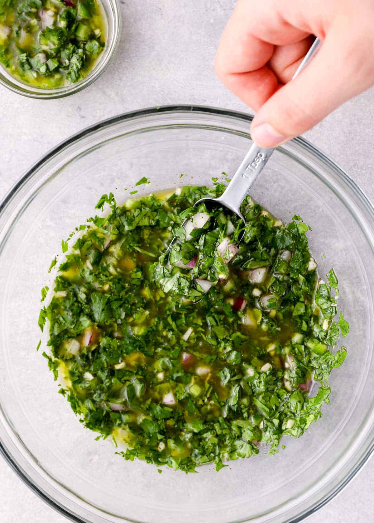 a spoon in a glass bowl full of cilantro lime fajita marinade
