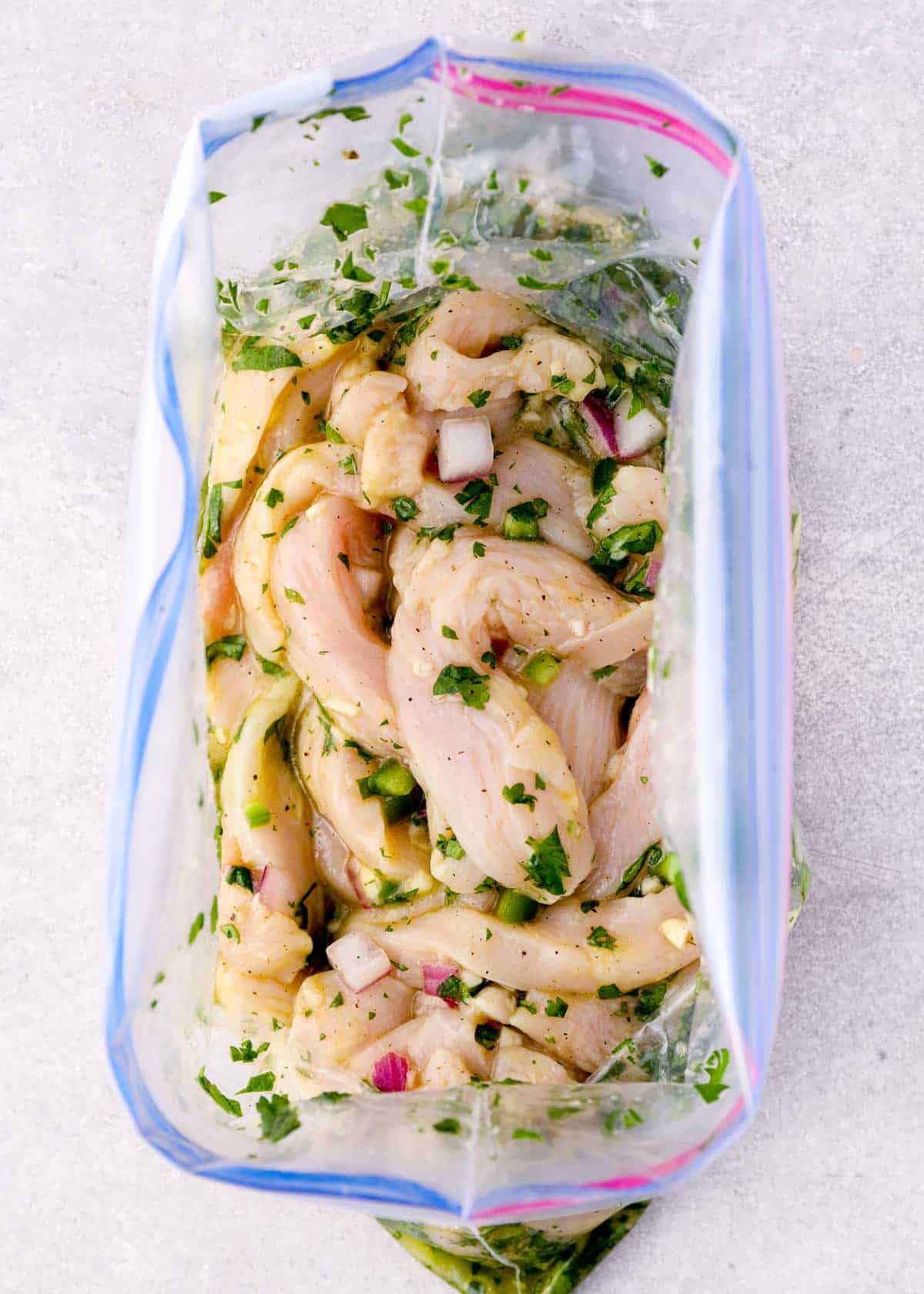 chicken strips coated in a cilantro lime marinade in a plastic bag