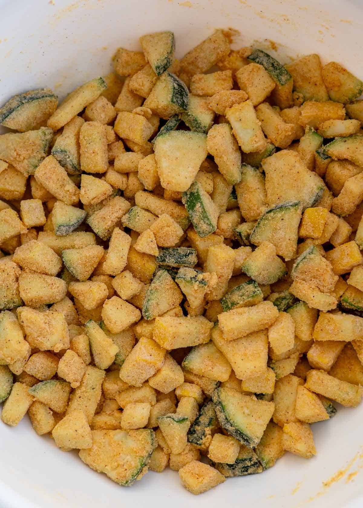 chopped vegetables covered in mayonnaise and seasoned fish breading in a white bowl