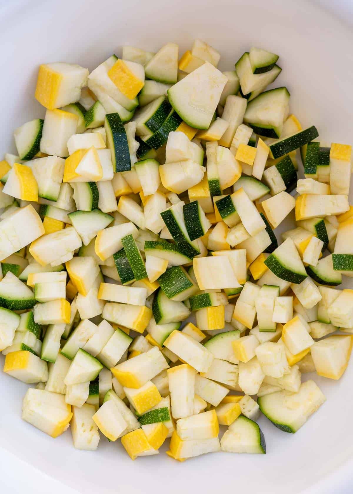Chopped zucchini and squash in a white mixing bowl