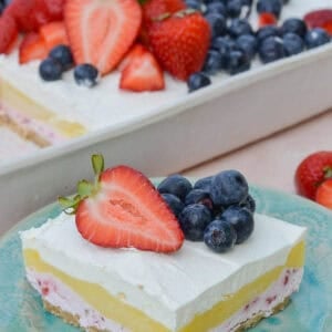 a strawberry cheesecake bar on a plate in front of the no-bake dessert