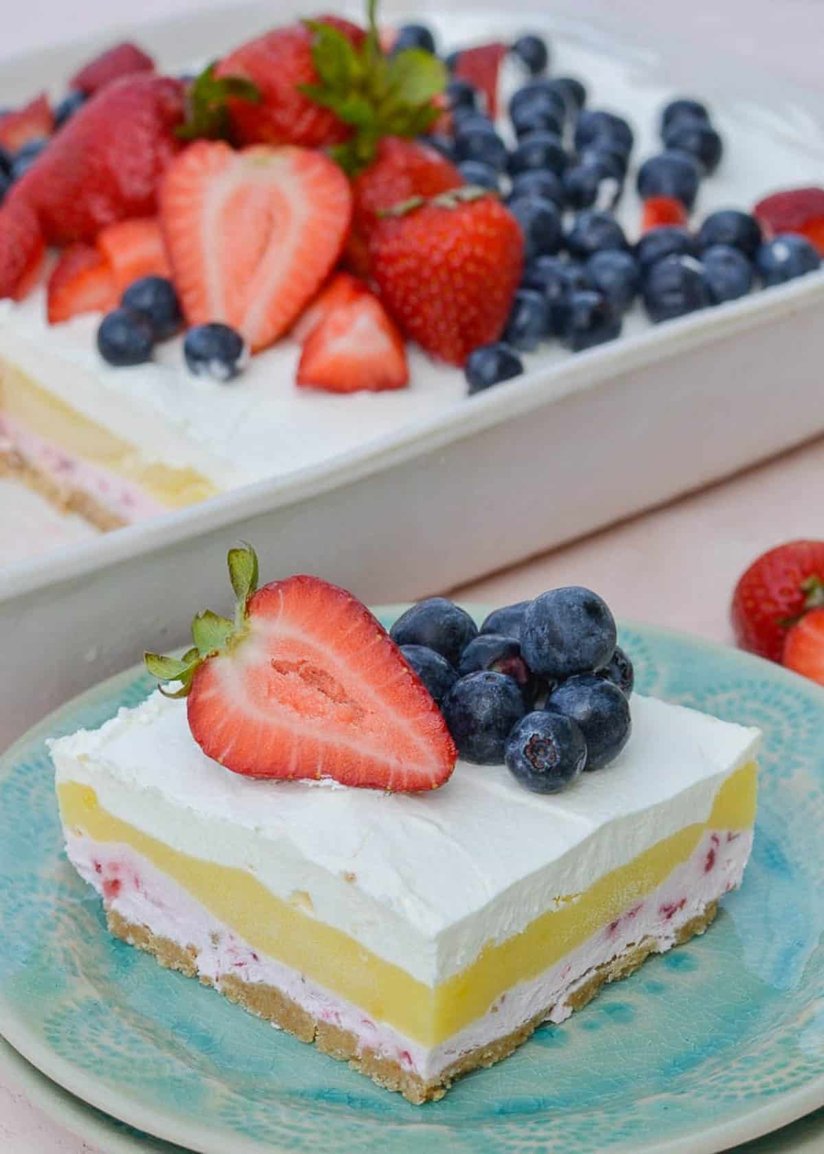 a strawberry cheesecake bar on a plate in front of the no-bake dessert