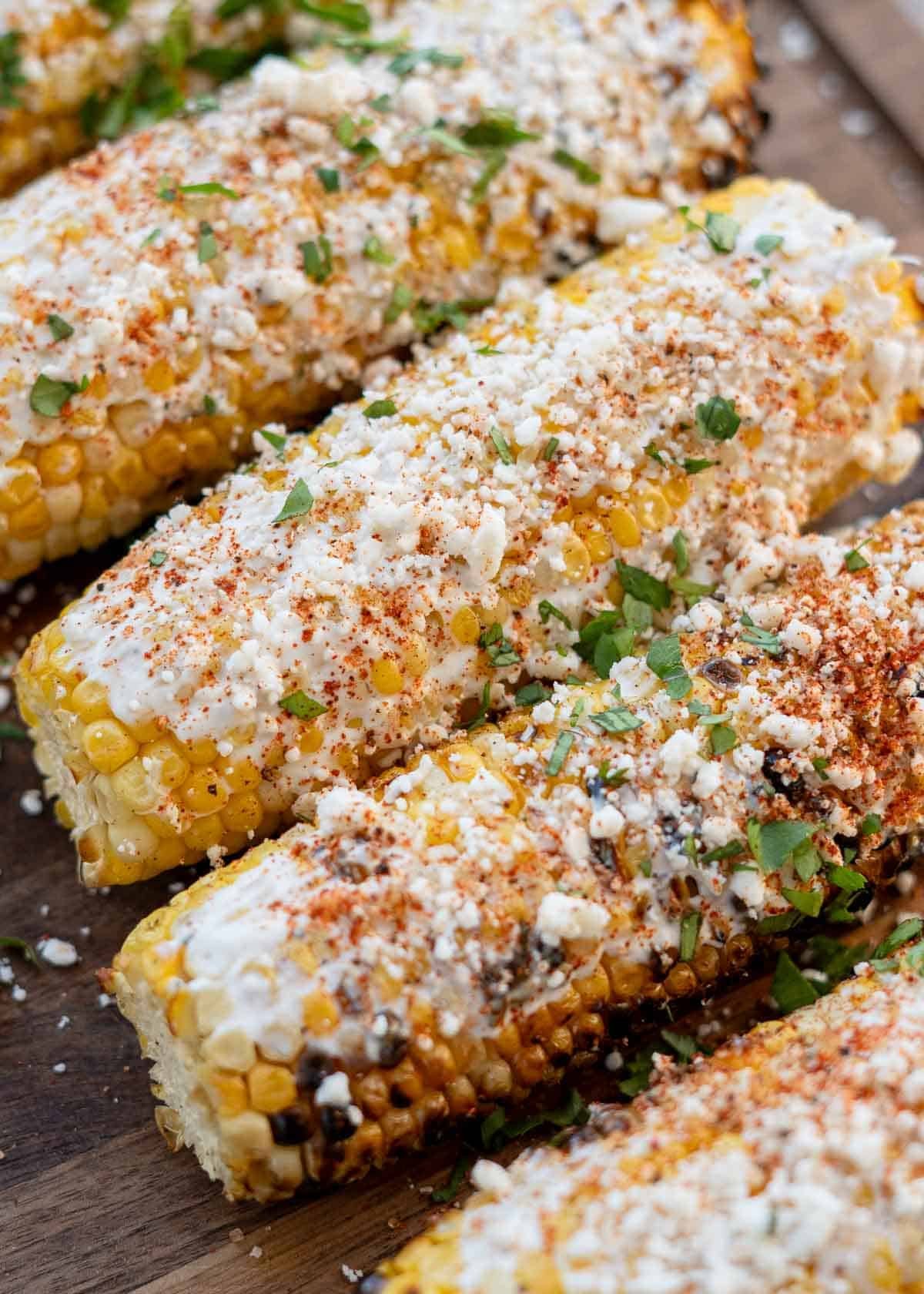 a side angle of grilled corn dressed with sour cream, cheese and spices