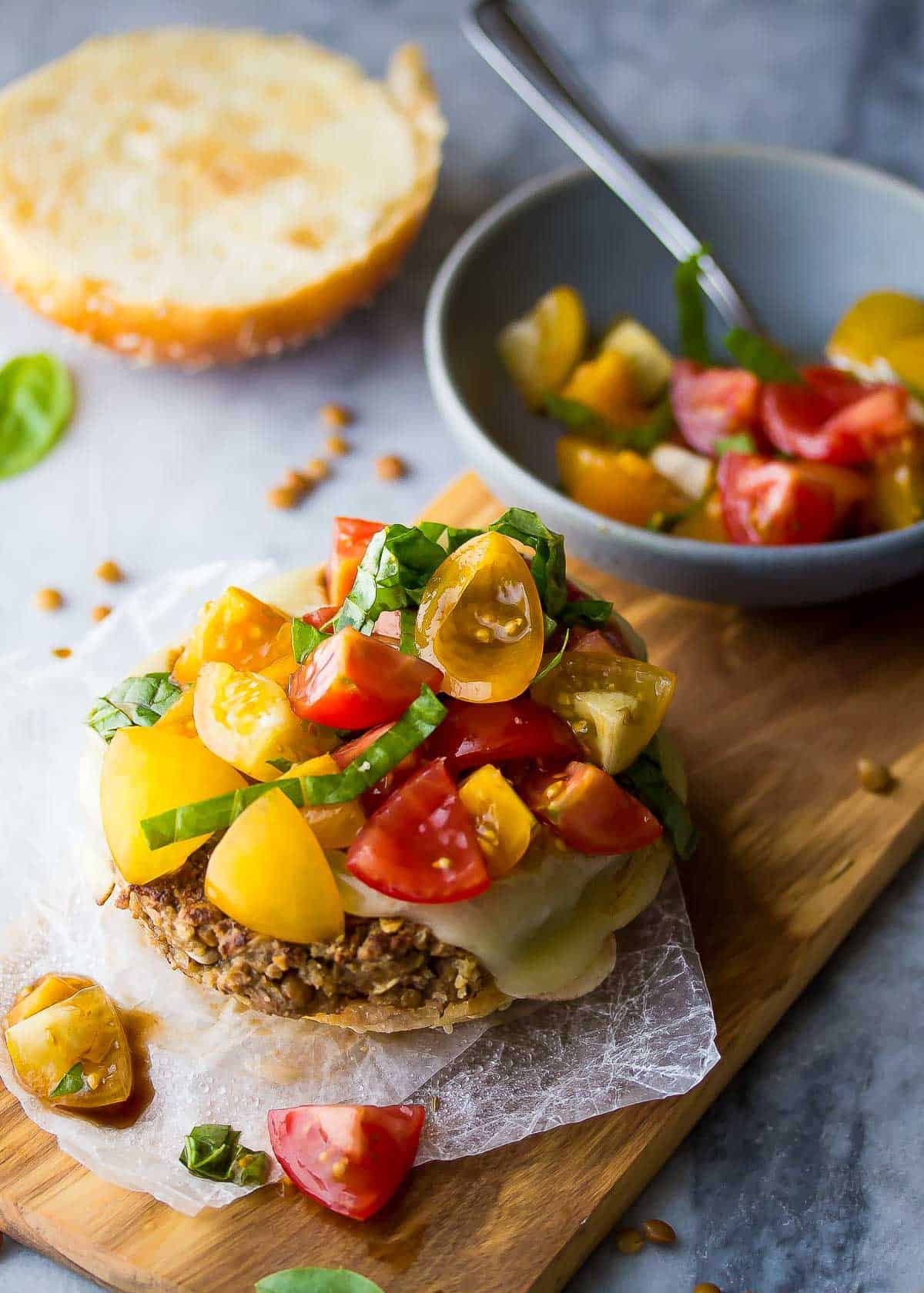 a lentil burger on a bottom bun, topped with tomato bruschetta