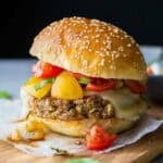 a delicious lentil burger topped with cheese and a tomato salsa on a wooden board