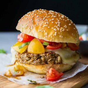 a delicious lentil burger topped with cheese and a tomato salsa on a wooden board