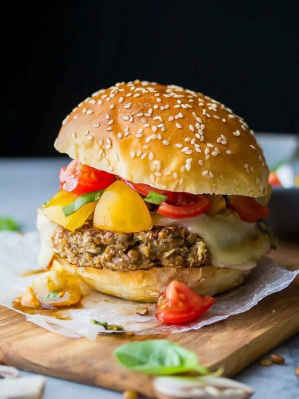 a delicious lentil burger topped with cheese and a tomato salsa on a wooden board
