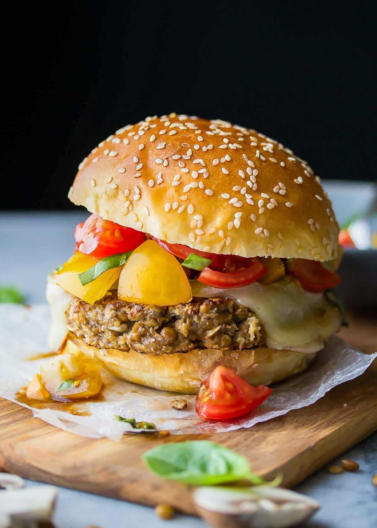 a delicious lentil burger topped with cheese and a tomato salsa on a wooden board