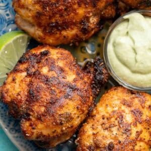 several air fryer boneless chicken thighs cooked to perfection with blackened seasoning, served with lime wedges and avocado crema
