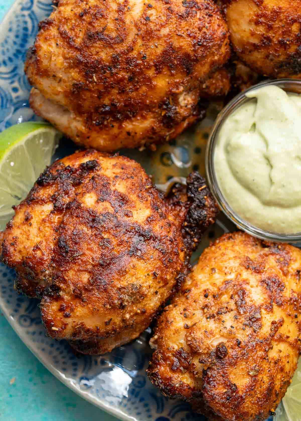 several air fryer boneless chicken thighs cooked to perfection with blackened seasoning, served with lime wedges and avocado crema