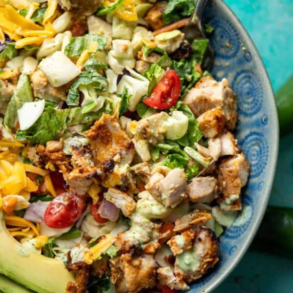 a mixed taco salad with juicy chicken, jalapeno ranch, and sliced avocado in a bowl with a fork