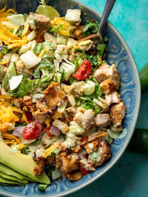 a mixed taco salad with juicy chicken, jalapeno ranch, and sliced avocado in a bowl with a fork