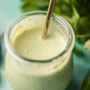 a small jar filled with spicy ranch dressing with jalapenos and cilantro
