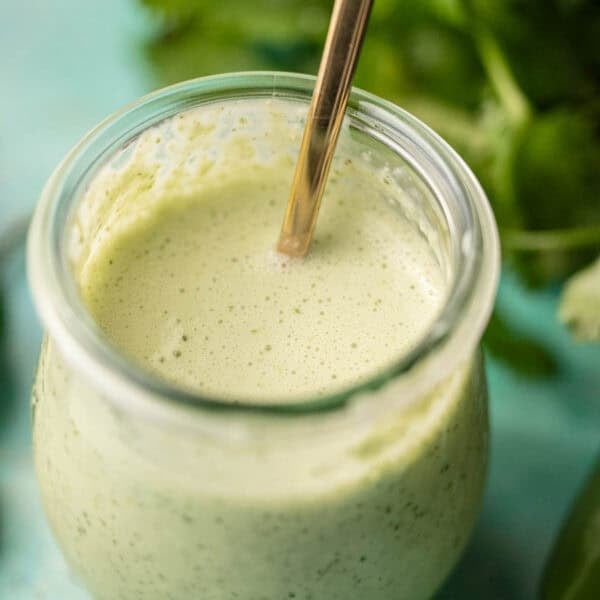 a small jar filled with spicy ranch dressing with jalapenos and cilantro