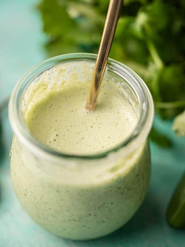 a small jar filled with spicy ranch dressing with jalapenos and cilantro
