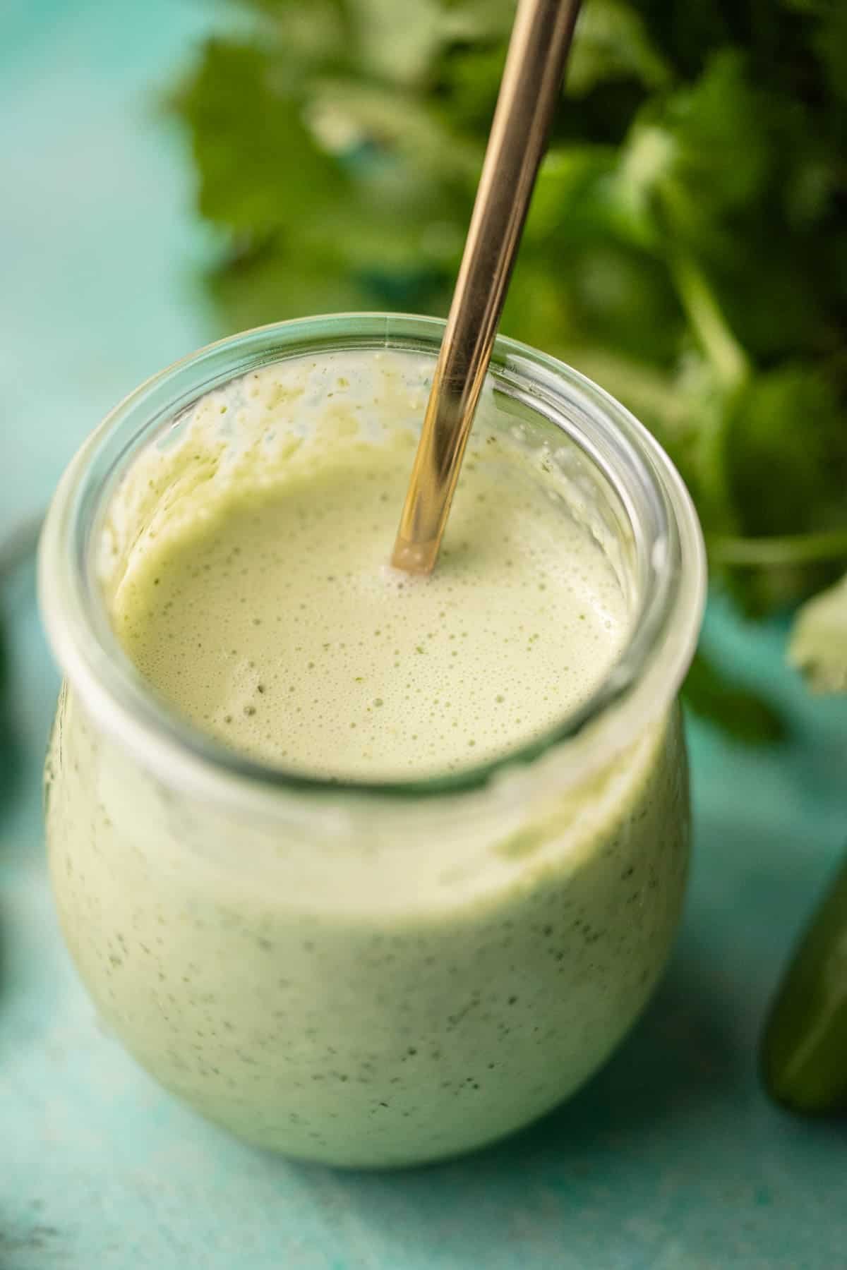 a small jar filled with spicy ranch dressing with jalapenos and cilantro