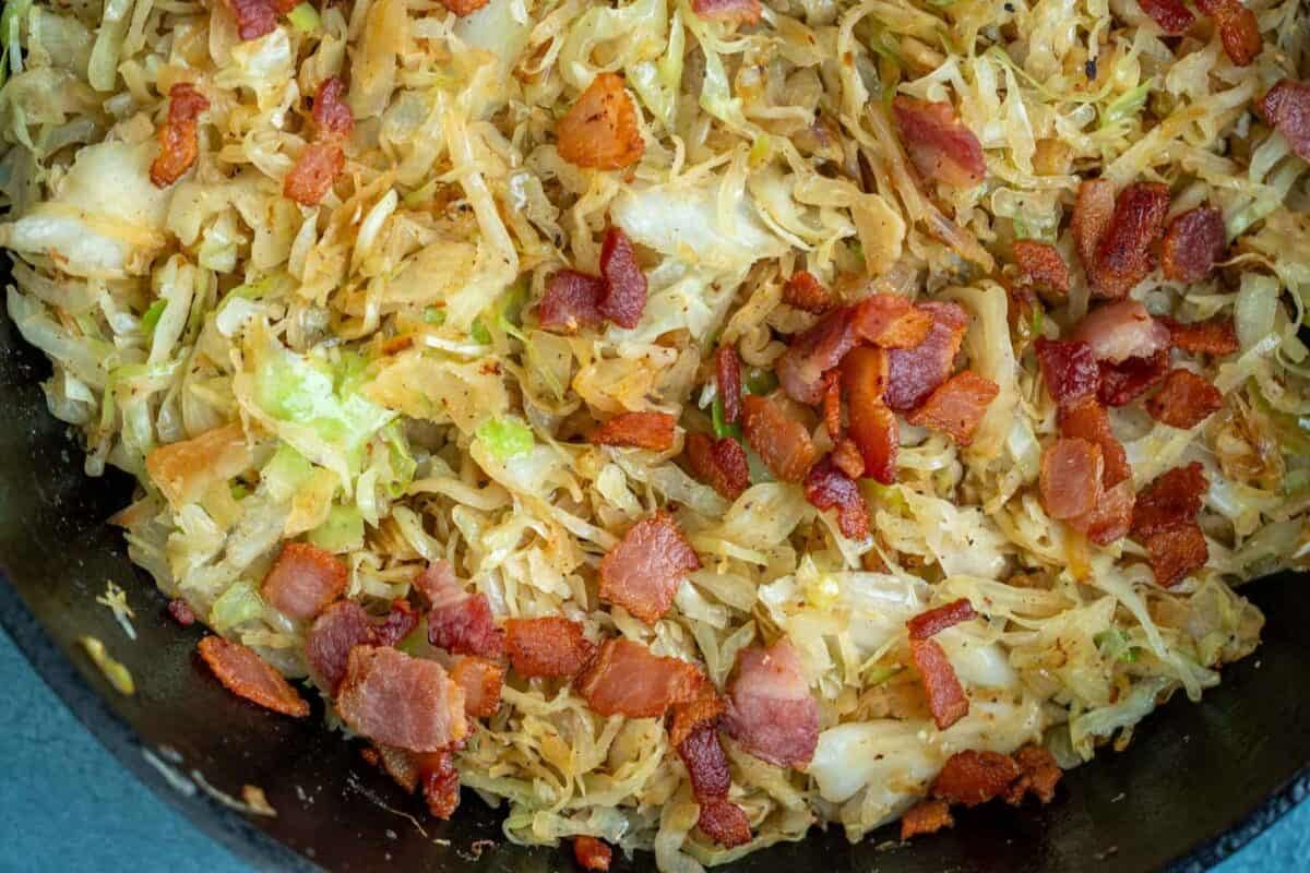 horizontal image showing crispy bacon mixed with fried shredded cabbage