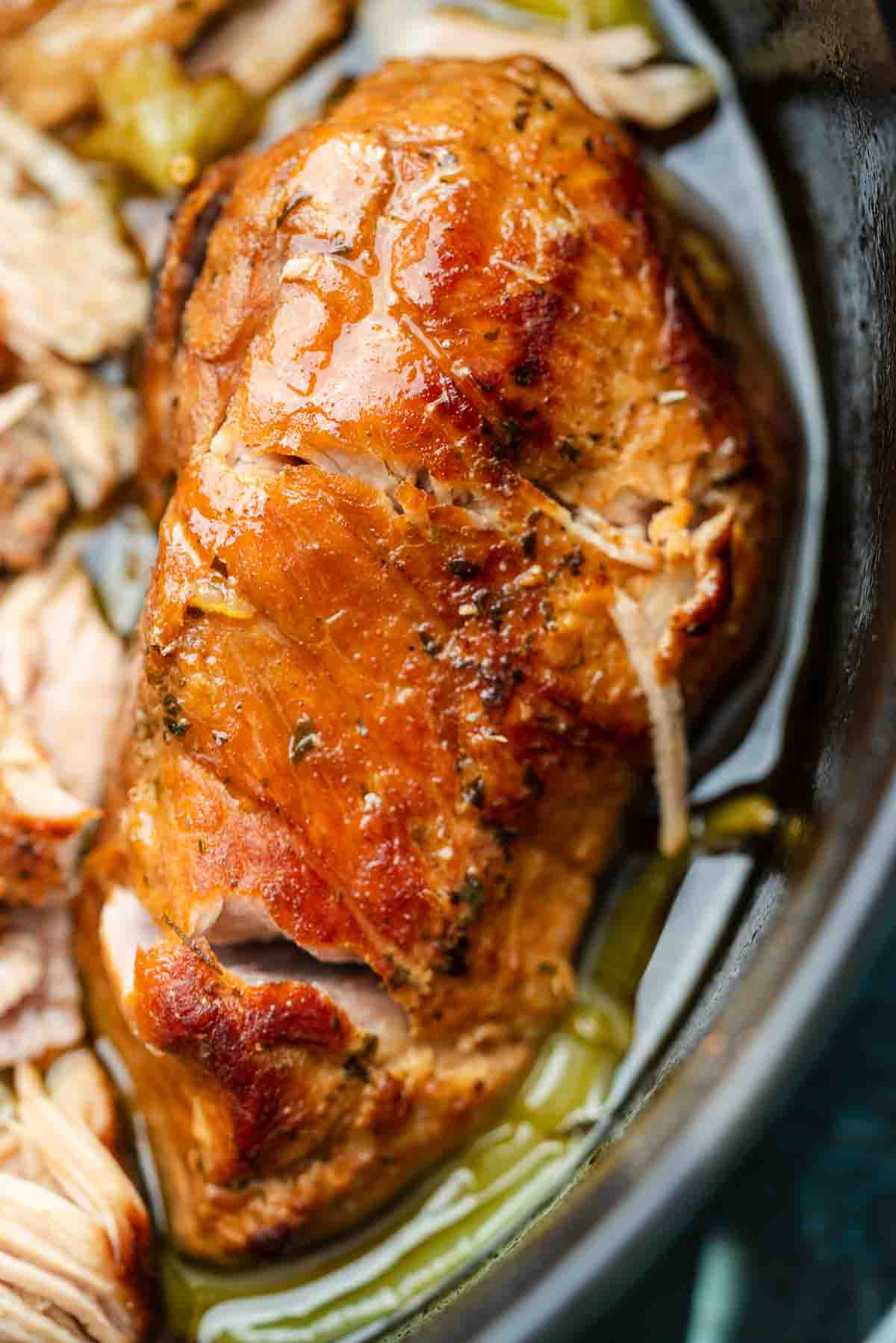 a super juicy pork roast simmering in a tangy broth