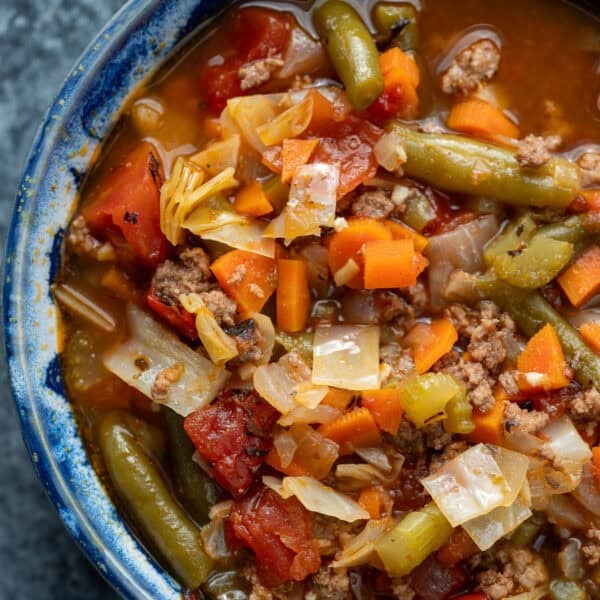 close up, overhead image of hamburger soup with cabbage in a blue bowl