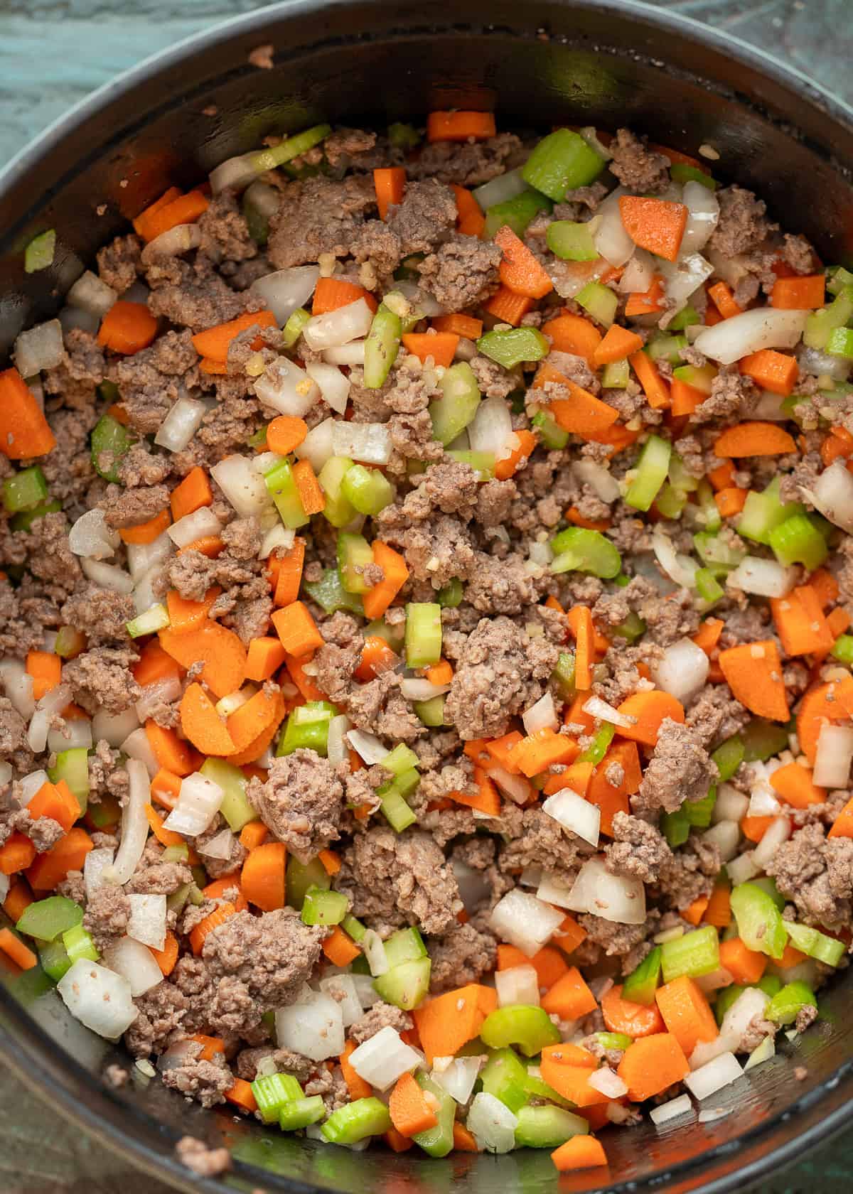 browned beef and cooked veggies in a black dutch oven