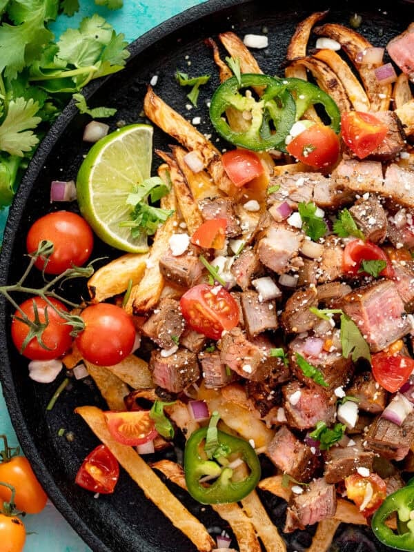 a plate loaded with carne asada on rutabaga fries and loaded with tomatoes, cilantro, cheese, and jalapenoes