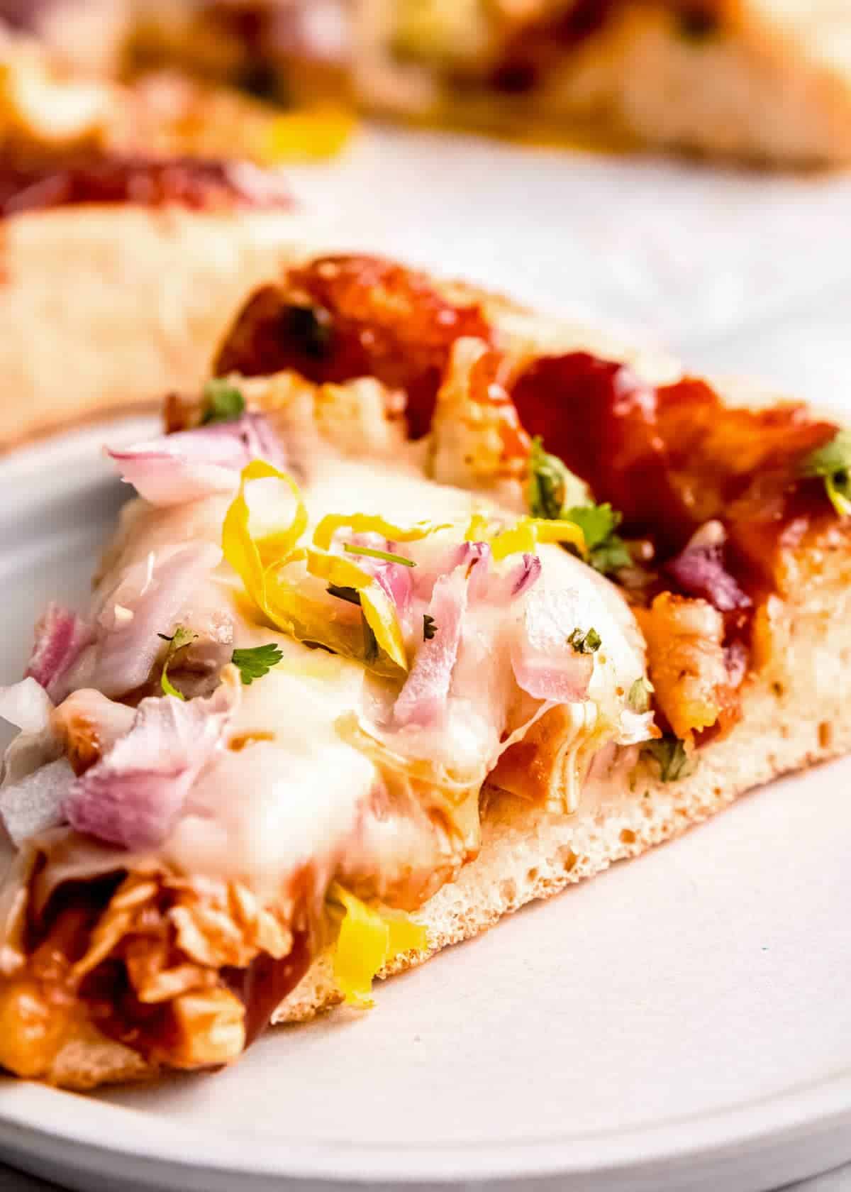 closeup of a slice of barbecue chicken pizza on a plate with the perfect crust