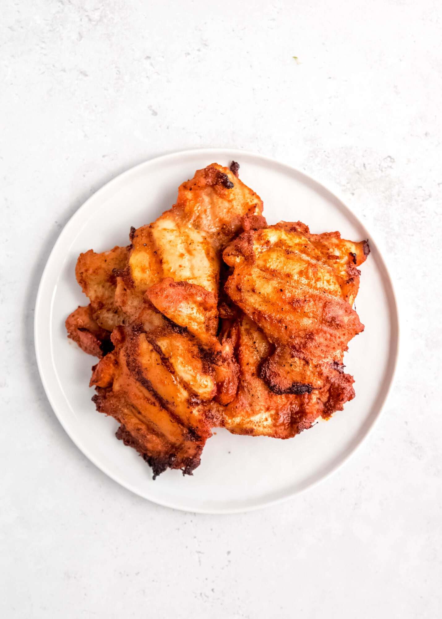 a white plate with a pile of grilled tostada chicken on top