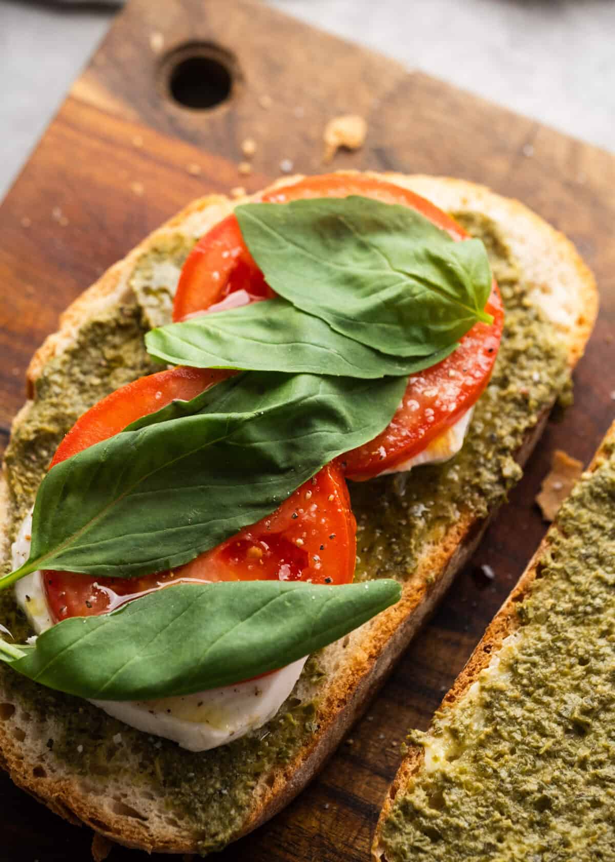 an open faced sandwich being topped with basil