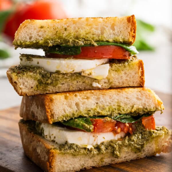 a freshly prepared pesto sandwich sitting on cutting board