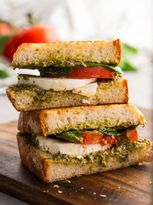 a freshly prepared pesto sandwich sitting on cutting board