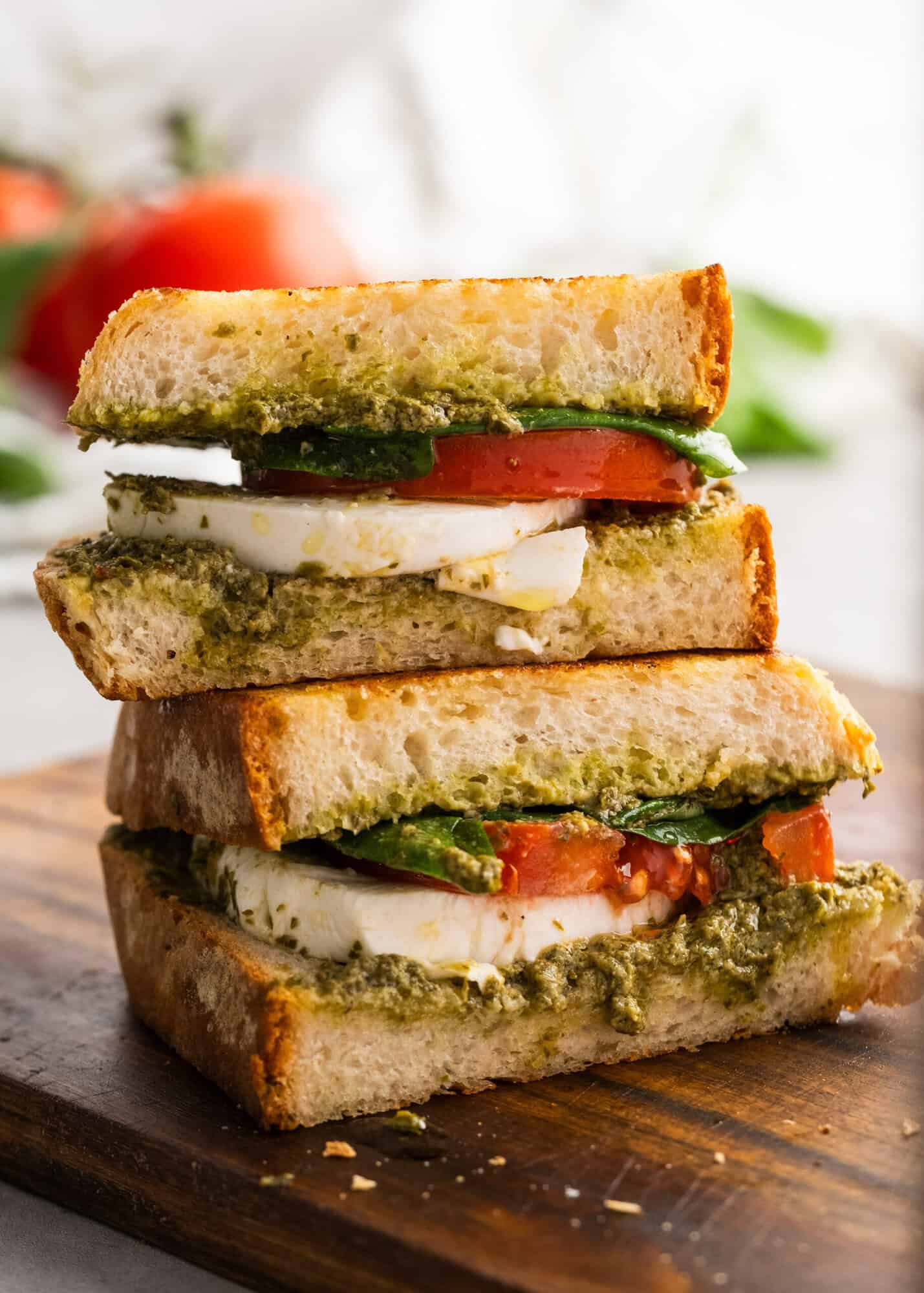 a freshly prepared pesto sandwich sitting on cutting board